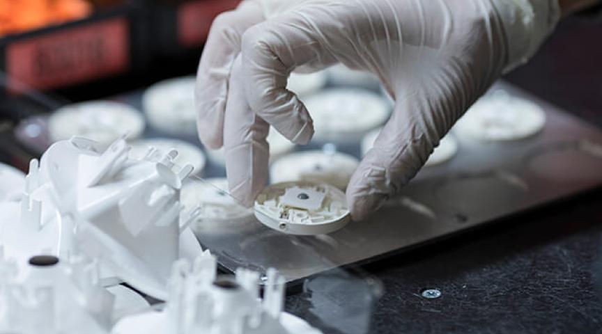 Gloved hand picking up manufactured part on assembly line